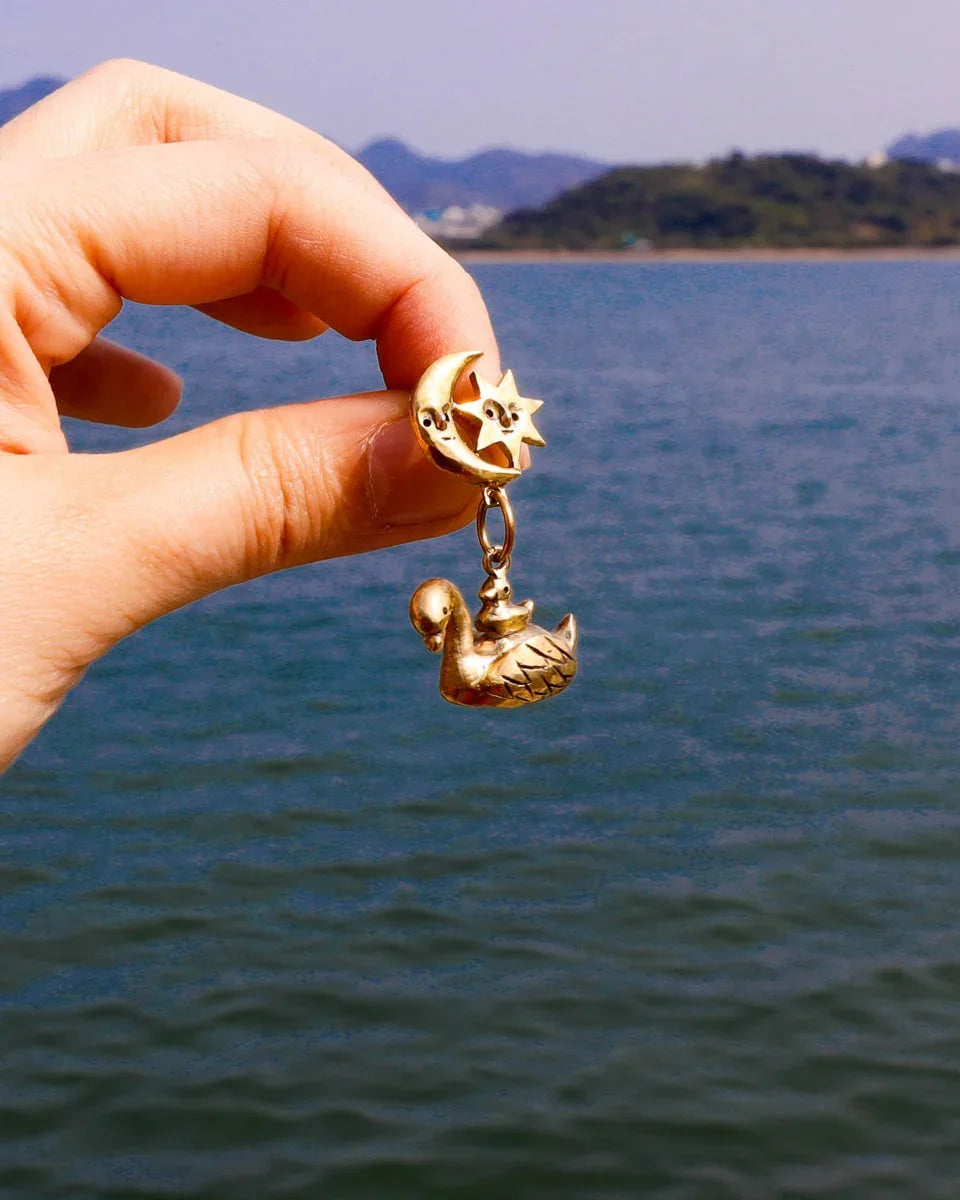 The Swan, cygnet and the moon earring featuring a baby swan riding on its parent, topped with a smiling moon and star. Handmade with lost-wax casting in brass—a tiny ode to love and cosmic connections