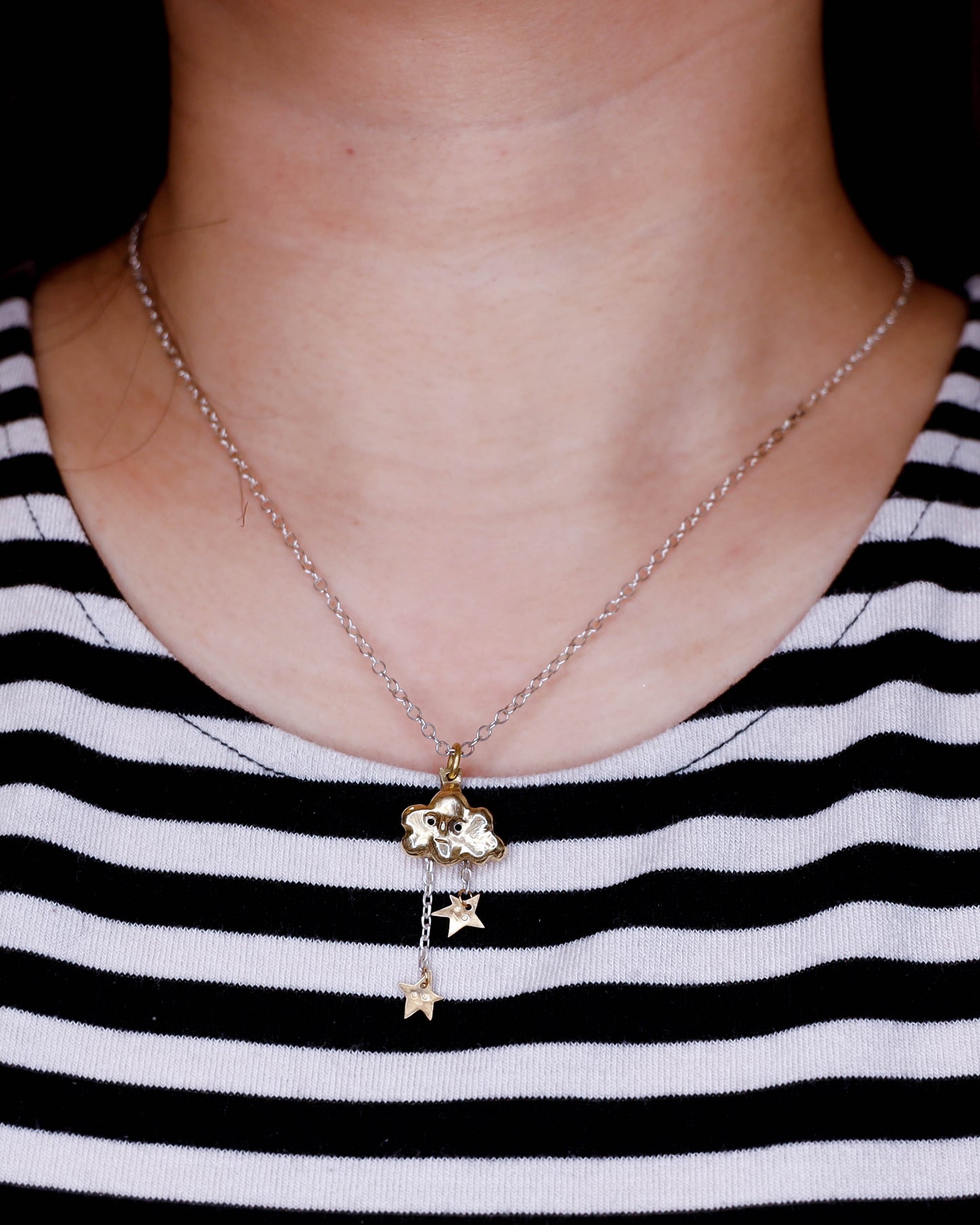 close up of ear wearing Shooting Stars Cloud pendant in solid brass and sterling silver