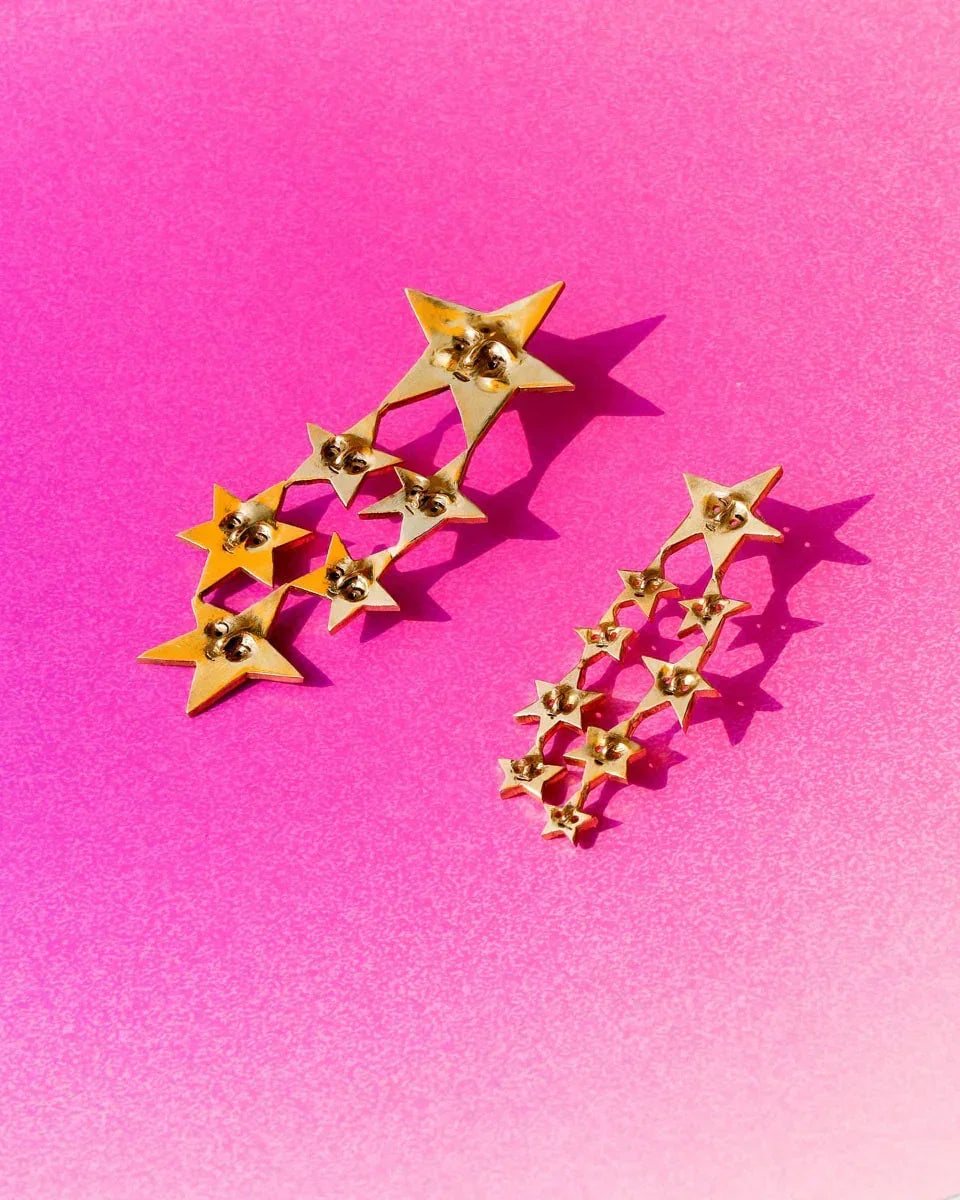 A Puke of Stars handmade earrings — a whimsical cluster of tiny stars, each with a unique face, linking together like cosmic characters. Wax-carved and cast in brass, this one-of-a-kind celestial jewellery piece celebrates connections with playful melancholy