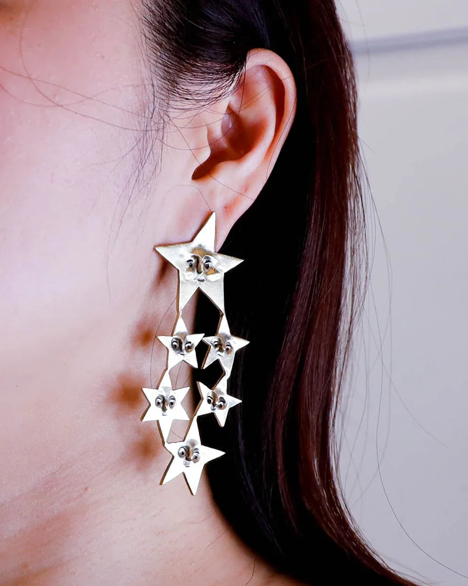 A Mega Puke of Stars’ bold earring — an expansive, intricate network of star characters, each with expressive faces, a statement celestial jewellery. Handcrafted with lost-wax casting in brass, this statement piece merges humour and heartache for those who wear their stories