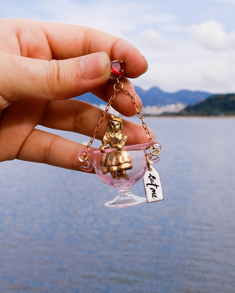 Handmade Alice in Wonderland earring/pendant with glass bowl, brass figure, and "Eat Me" vitreous enamel tag, handmade by fake plastic love