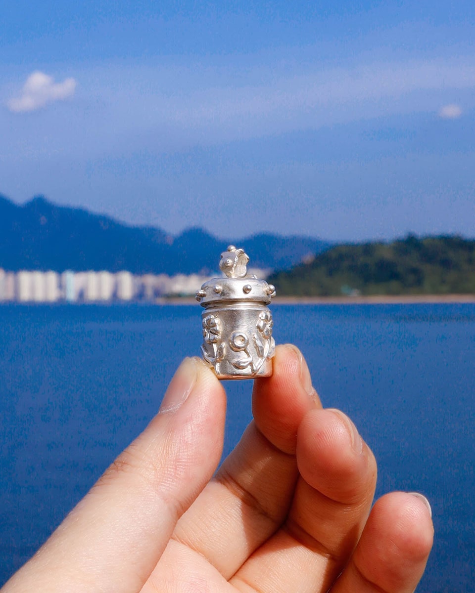 A solid sterling silver container locket pendant with flower, hand-carved with wax cast into silver, with a functional hinged lid. Handmade by fake plastic love