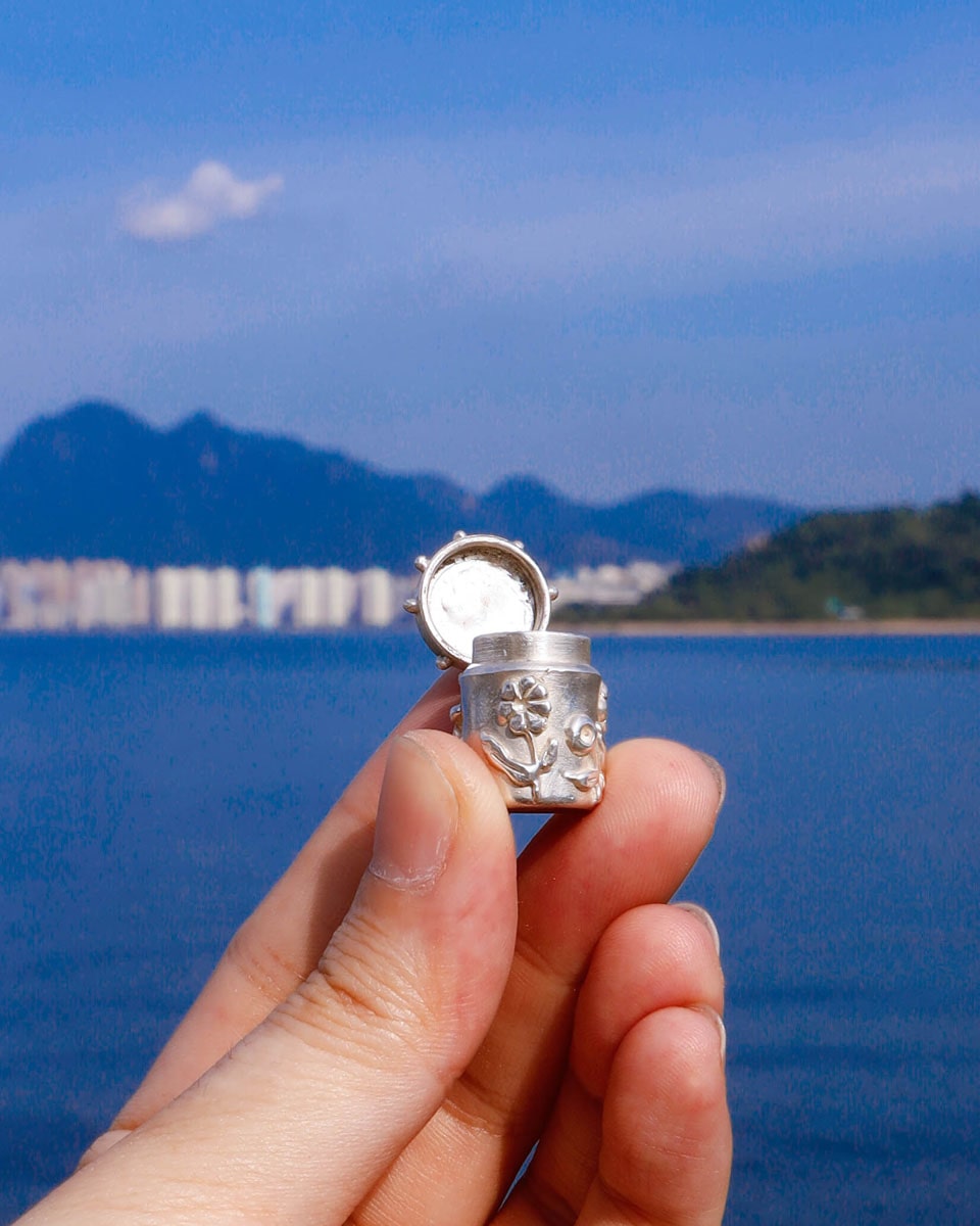 A solid sterling silver container locket pendant with flower, hand-carved with wax cast into silver, with a functional hinged lid. Handmade by fake plastic love