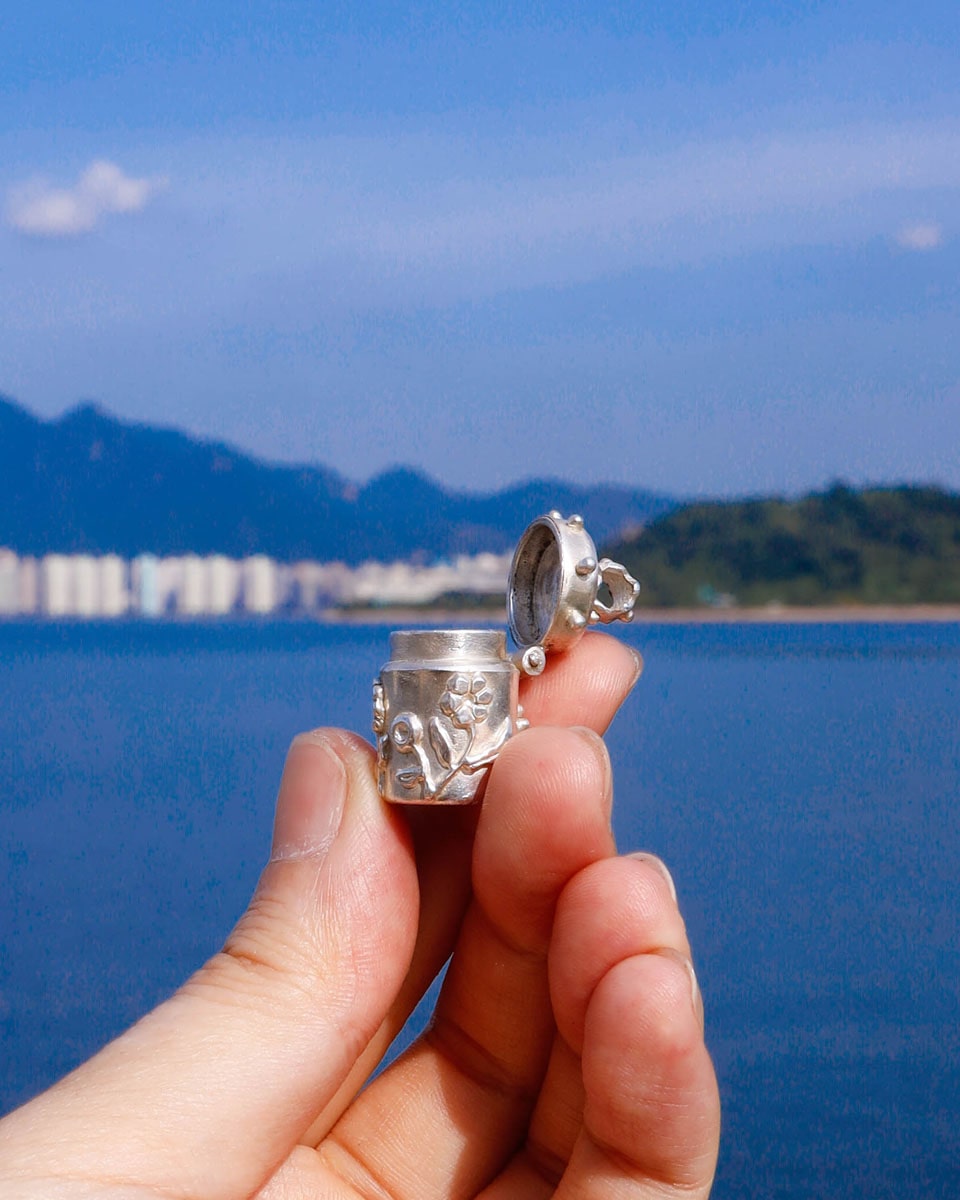 A solid sterling silver container locket pendant with flower, hand-carved with wax cast into silver, with a functional hinged lid. Handmade by fake plastic love