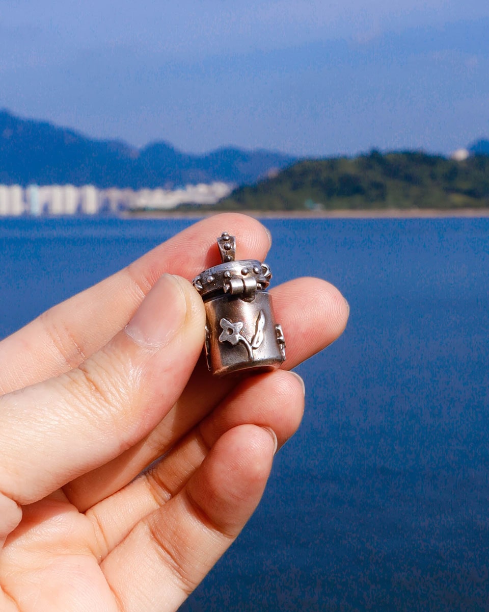 A solid sterling silver container locket pendant with floral details in patina finish, hand-carved with wax cast into silver, with a functional hinged lid. Handmade by fake plastic love