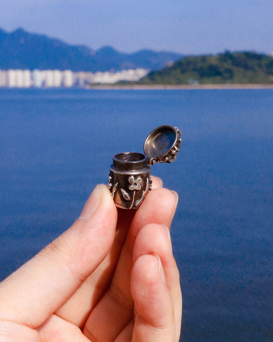 A solid sterling silver container locket pendant with floral details in patina finish, hand-carved with wax cast into silver, with a functional hinged lid. Handmade by fake plastic love