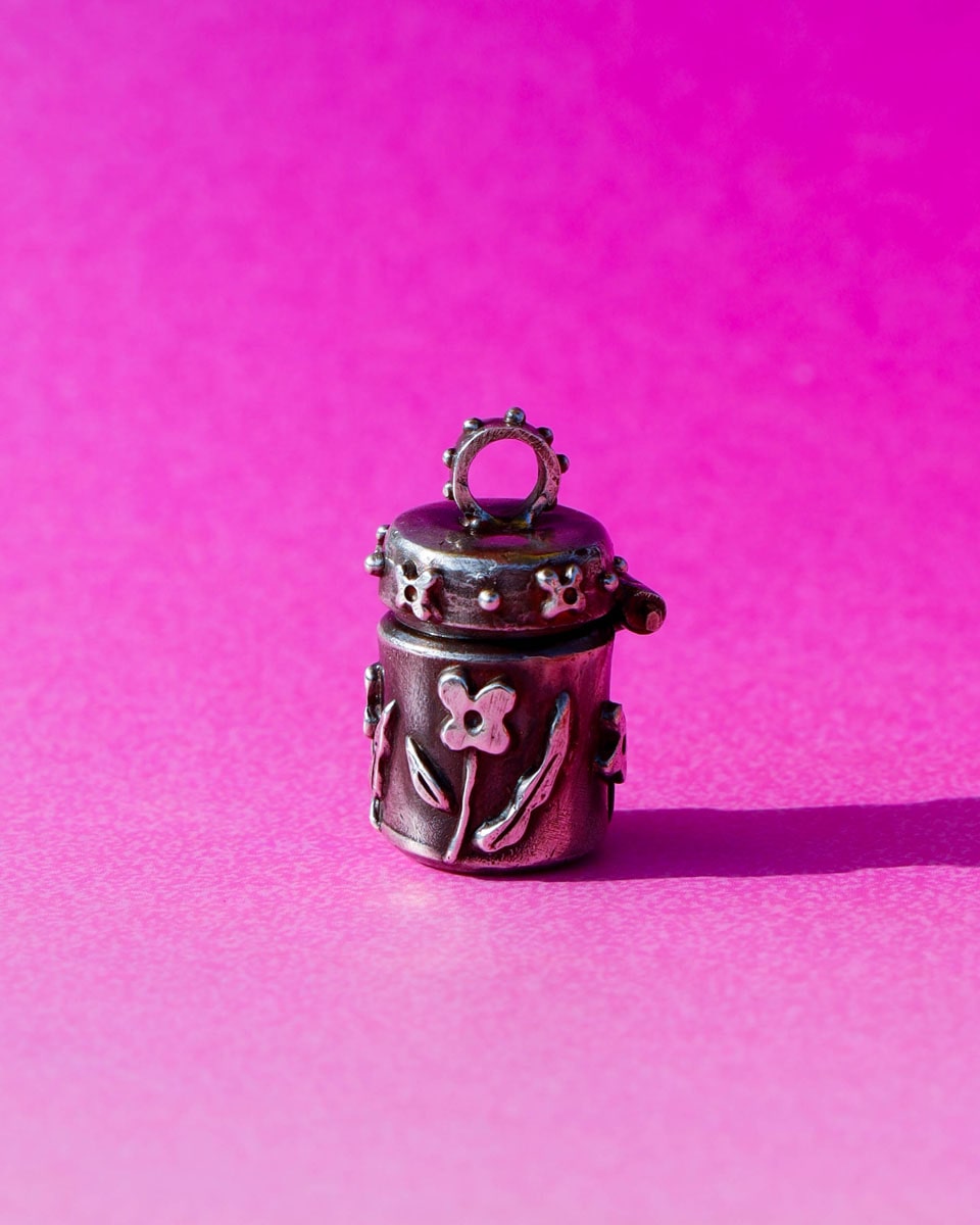 A solid sterling silver container locket pendant with floral details in patina finish, hand-carved with wax cast into silver, with a functional hinged lid. Handmade by fake plastic love