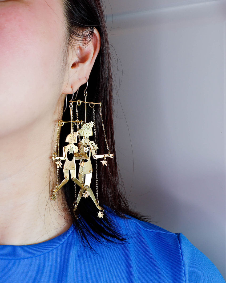 Close-up of mini brass articulated puppet earrings with stars, handmade kinetic jewelry
