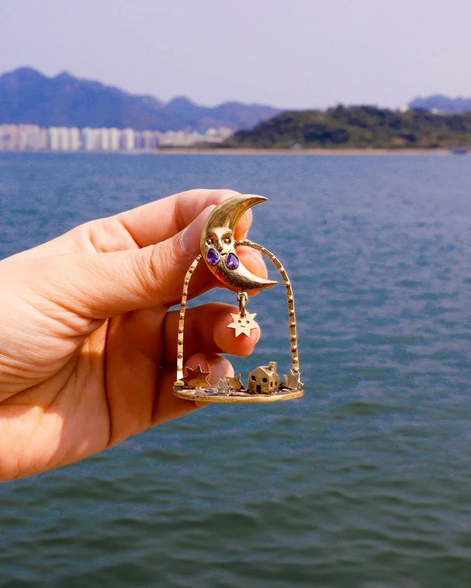 "Where The Fallen Stars Return As Tides" brass statement earrings: a moon with purple CZ tears drops stars into an ocean scene with a tiny house. Wearable poetry by fake plastic love