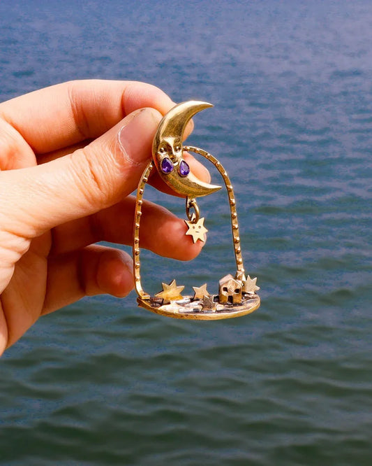 "Where The Fallen Stars Return As Tides" brass statement earrings: a moon with purple CZ tears drops stars into an ocean scene with a tiny house. Wearable poetry by fake plastic love