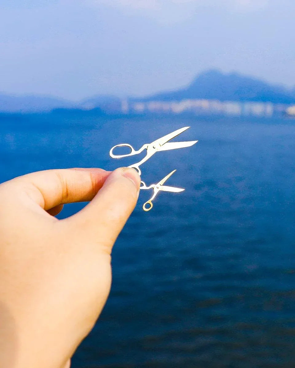 Handmade brass earrings shaped like miniature fabric scissors with kinetic blades