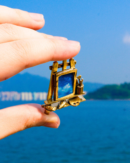 Close-up of miniature artist easel with paint brushes, palette, and detailed painting tools