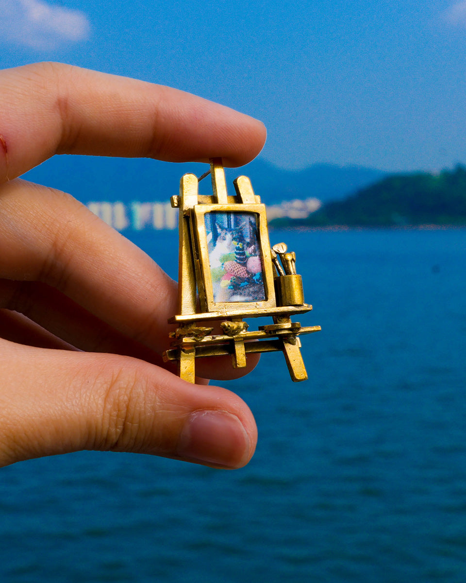 Miniature painting stand earring in brass with artist easel, brushes, palette, and paint tubes