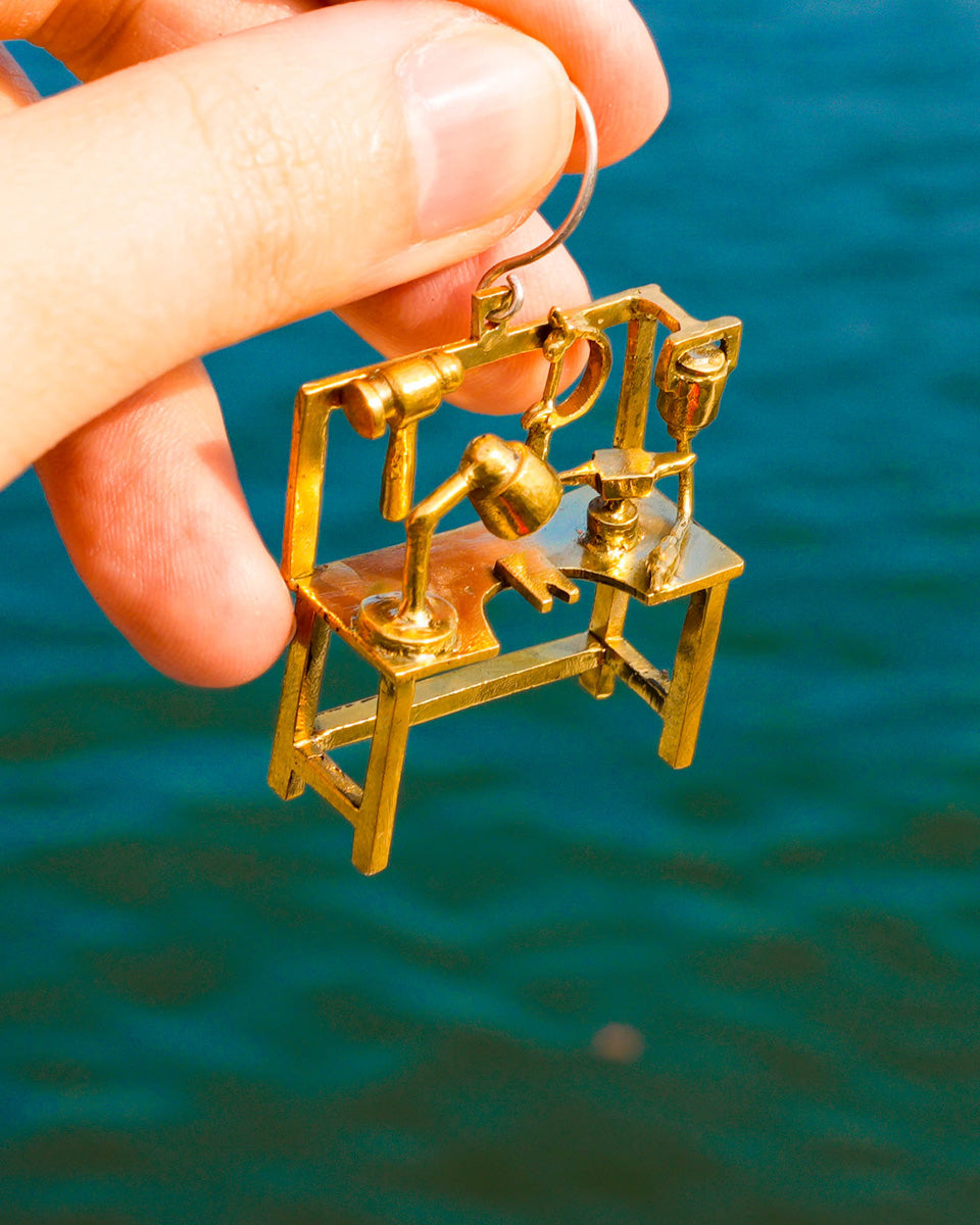 Close-up of miniature metalsmith bench with anvil, hammer, saw frame, and flex shaft details