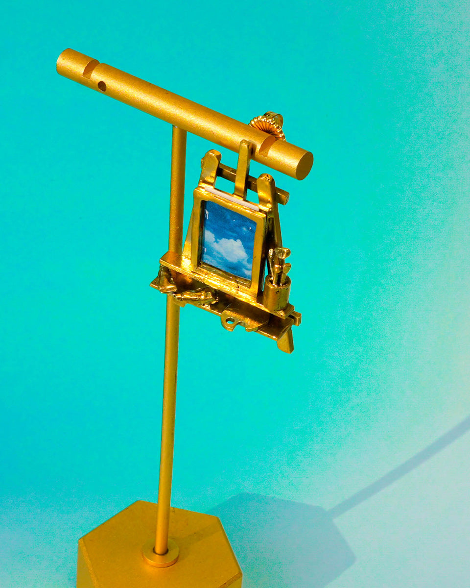 Close-up of miniature artist easel with paint brushes, palette, and detailed painting tools