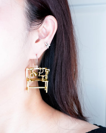 Miniature jeweller’s bench statement earring worn on ear, handcrafted studio-inspired jewelry
