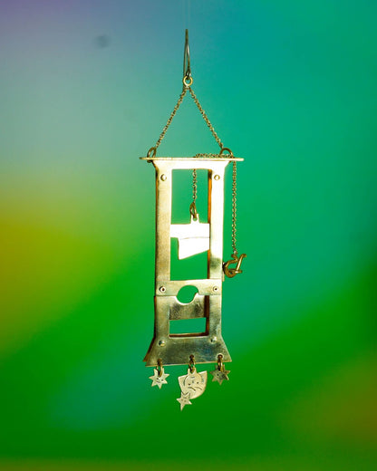 Handmade brass guillotine earring with a movable blade, chain mechanism, dangling stars, and a suspended face inspired by the Person Controlled by the Stars series.