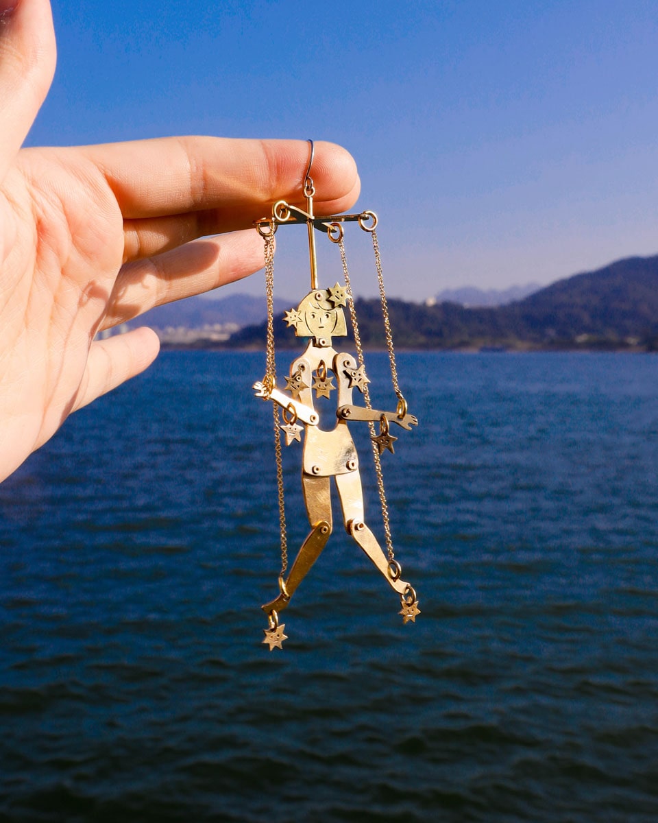 Articulated brass puppet earring "The Person Controlled by the Stars" with moving handsaw joints


