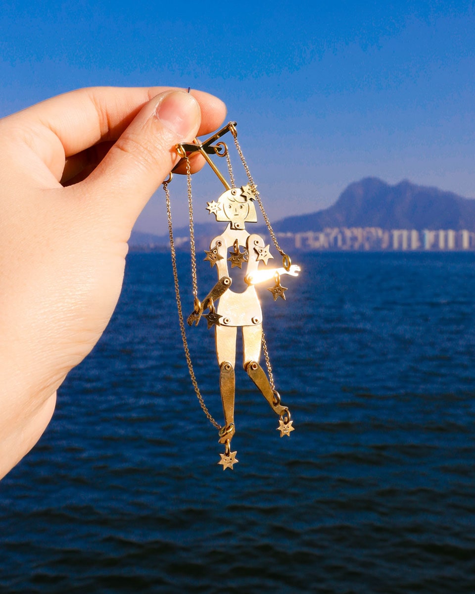Articulated brass puppet earring "The Person Controlled by the Stars" with moving handsaw joints