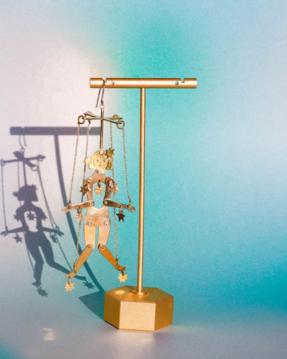 Articulated brass puppet earring "The Person Controlled by the Stars" with moving handsaw joints