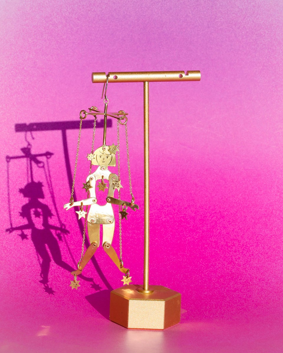 Articulated brass puppet earring "The Person Controlled by the Stars" with moving handsaw joints