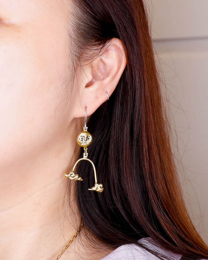 model wearing the Moon's Blessing celestial dangle earring in solid brass, featuring a full moon and two auspicious cloud