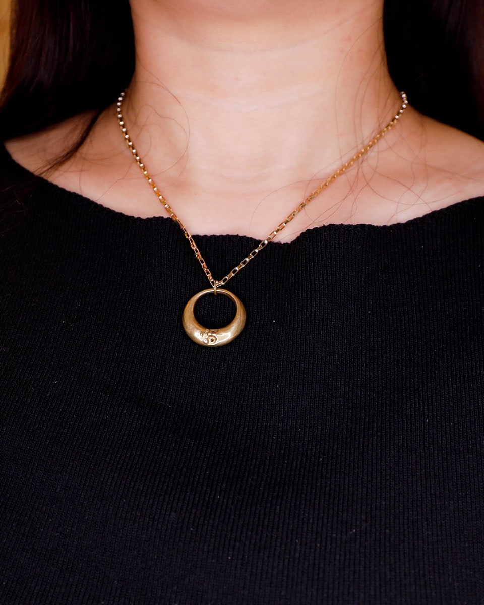 Solid brass Celestial full Moon pendant on woman for Mid-Autumn Festival, featuring moon faces on the sides symbolizing family reunion and harmony
