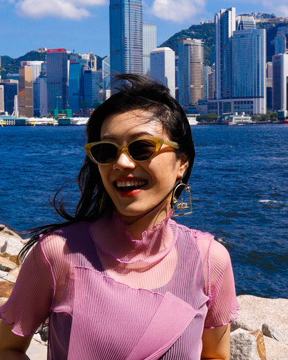 woman wearing brass-framed merry-go-round earring with floral design on the frame, empty playground earring with kinetic element. made by fake plastic love