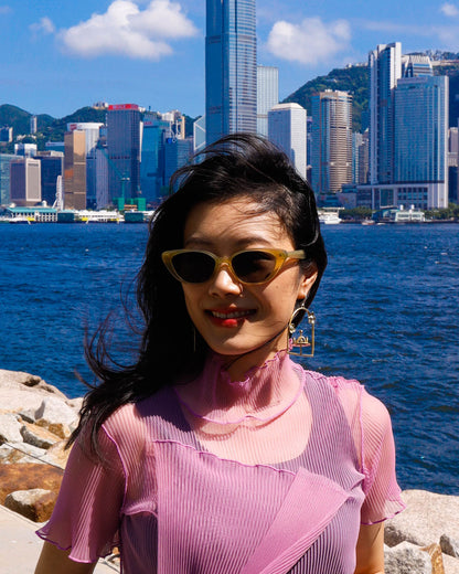woman wearing brass framed merry-go-round earring with floral design on the frame, empty playground earring with kinetic element. made by fake plastic love