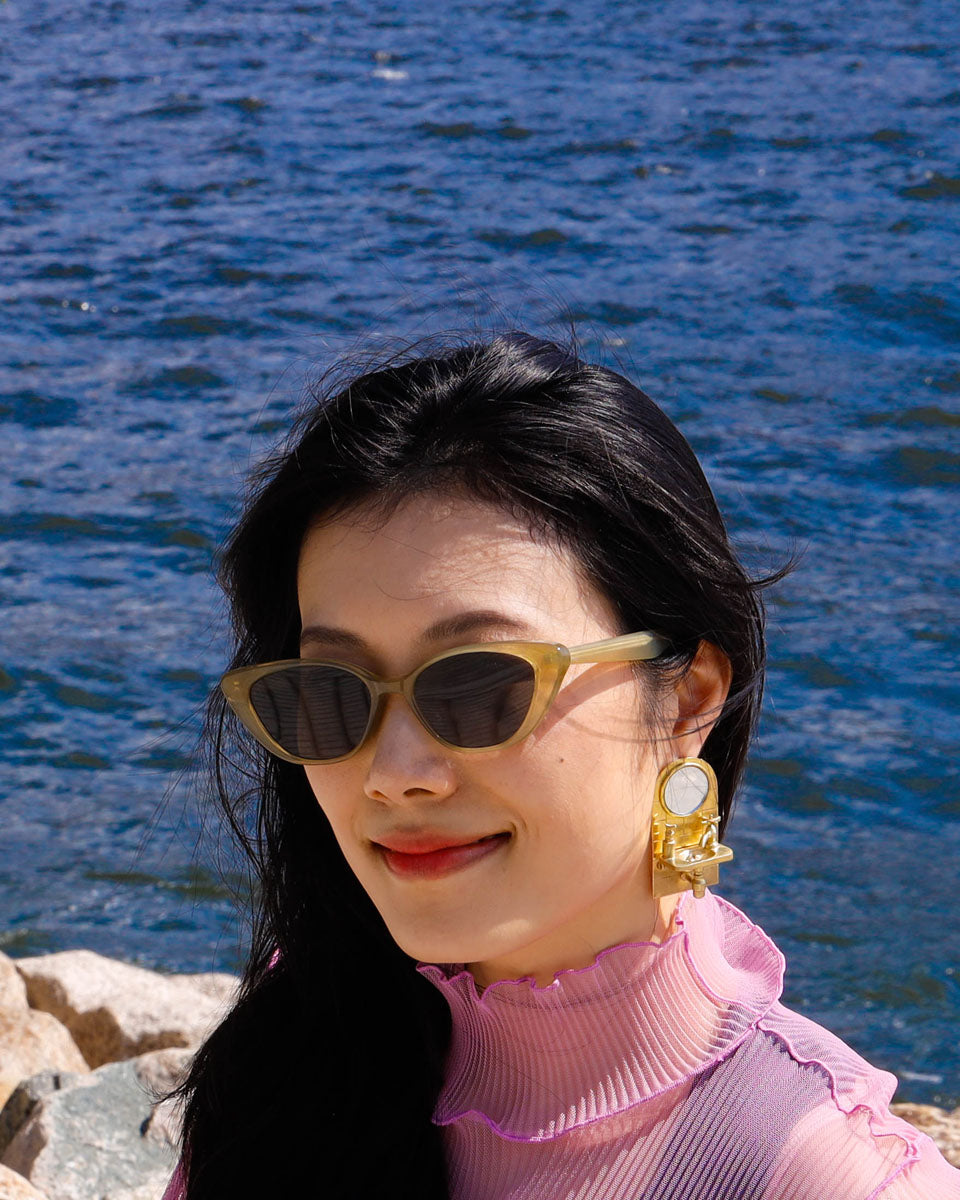girl wearing a miniature sink statement earring, handcrafted in brass with a functional mirror