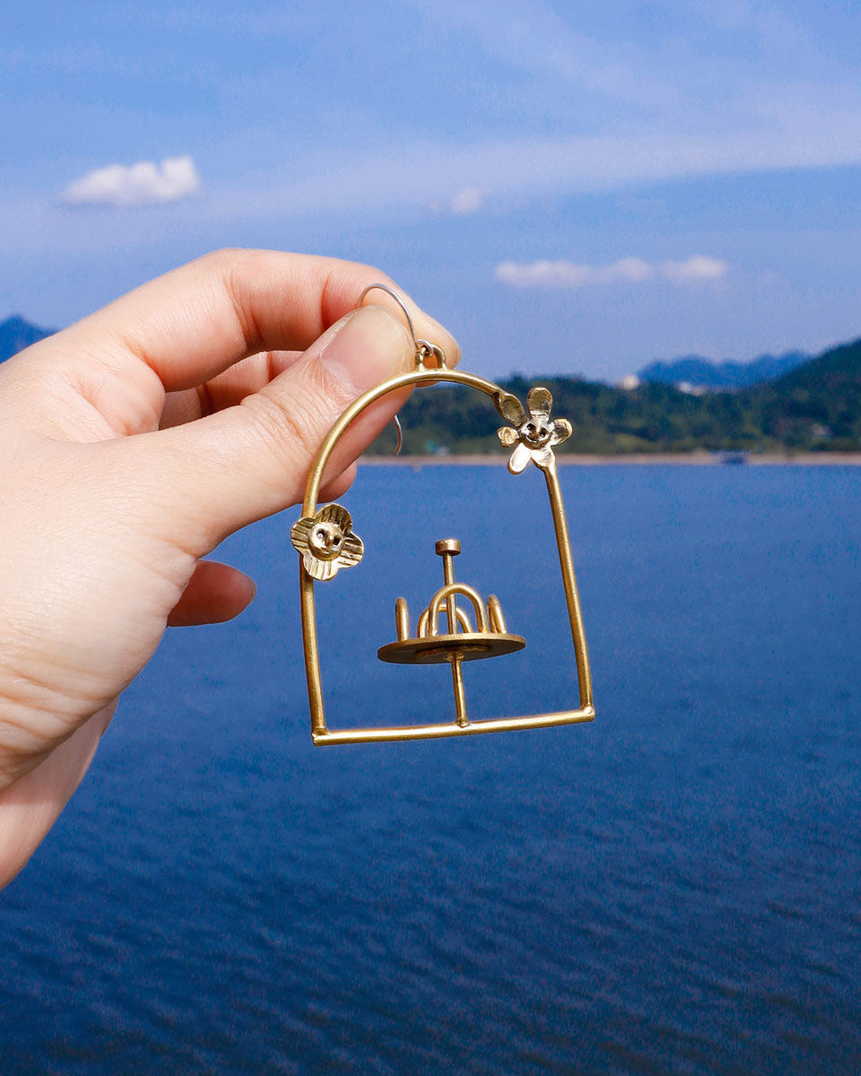 Brass-framed merry-go-round earring with floral design on the frame, empty playground earring with kinetic element. made by fake plastic love
