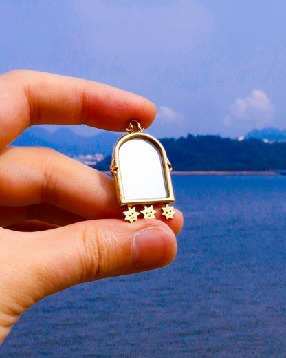 hand holding a Miniature arched shape mirror pendant in brass 