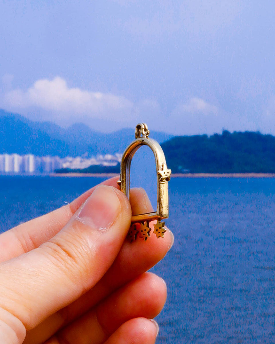 the side detail of a brass arched-shaped charm with stars design, handmade jewellery with a functional mirror