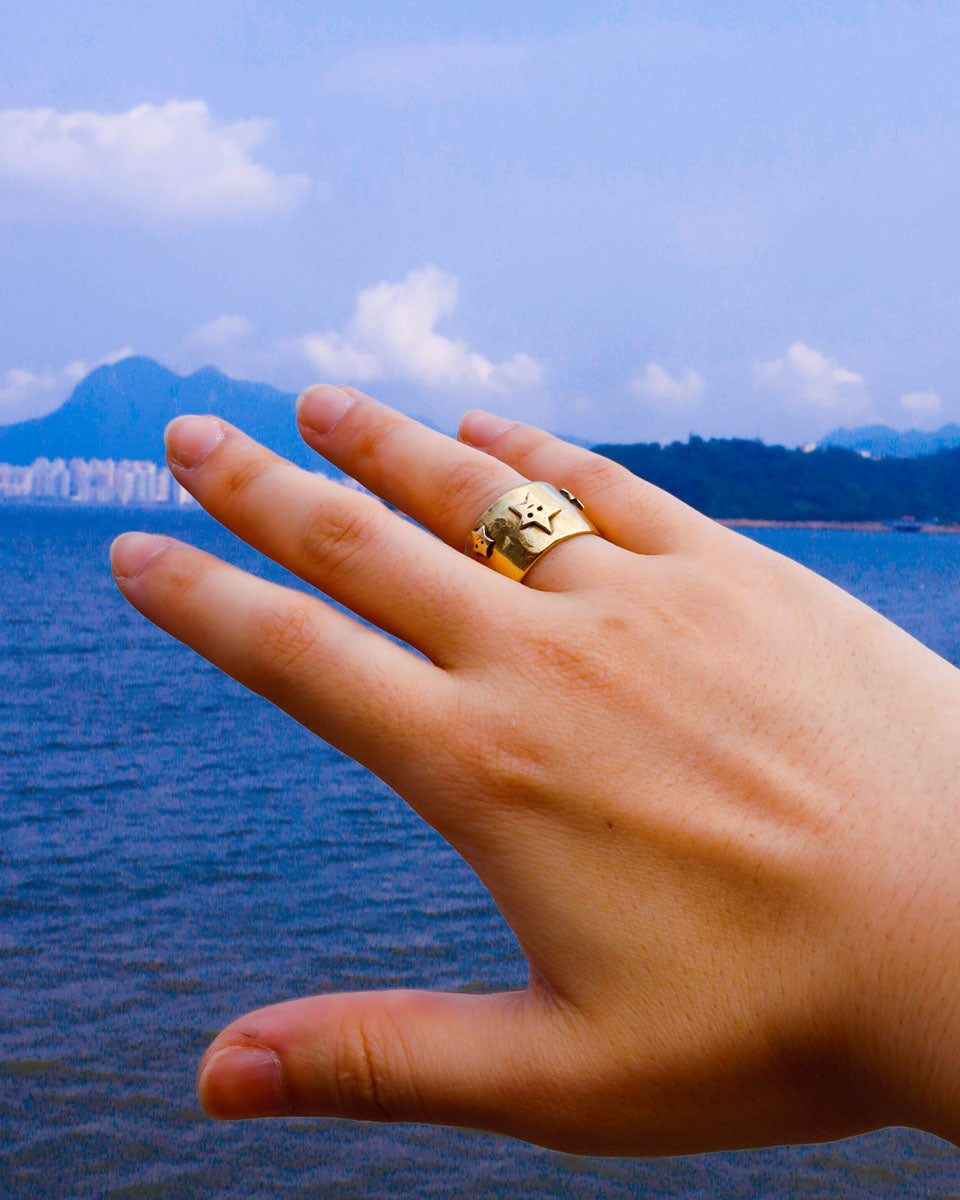 Hand wearing many stars ring a wide band ring in brass with star designs