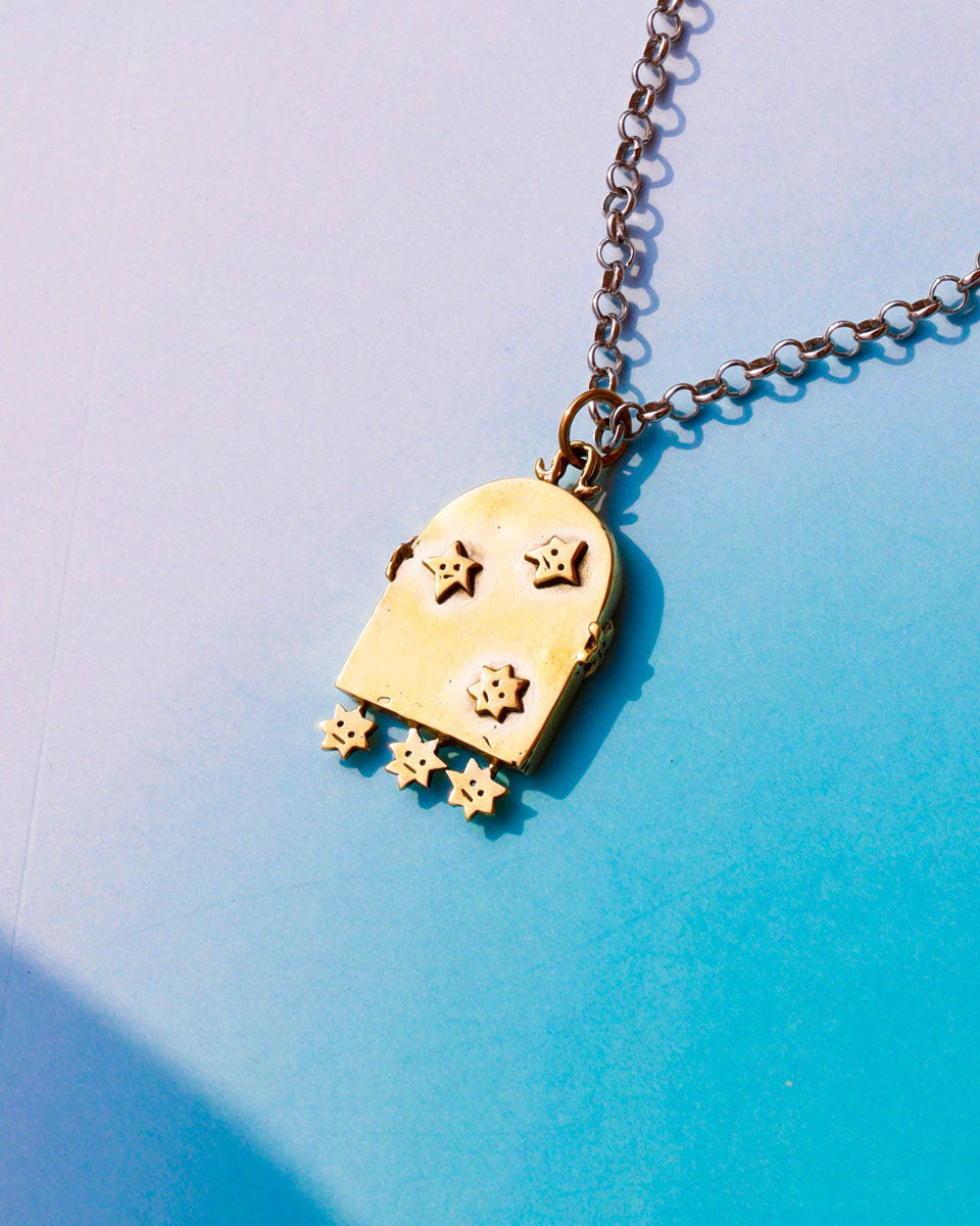 Gold arched shaped mirror pendant necklace with star designs on a gradient blue background