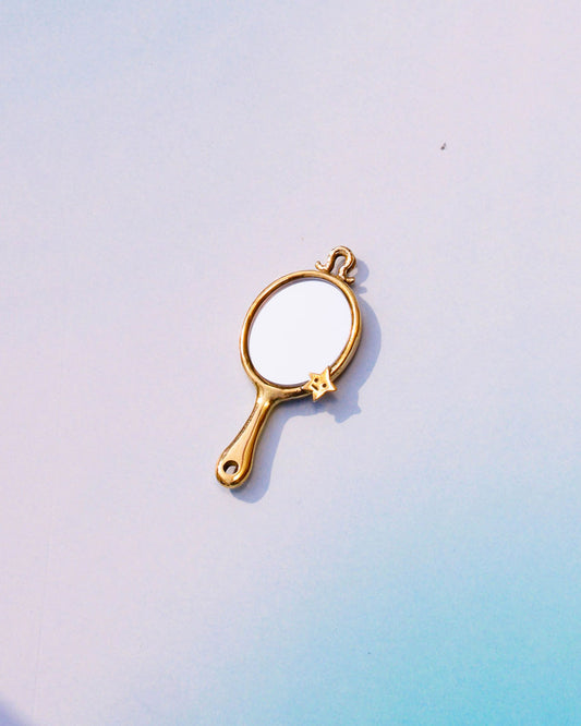 Handcrafted miniature tiny hand mirror made in solid brass, featuring engraved star motifs on both sides and a functional reflective mirror surface, shown as wearable charm 