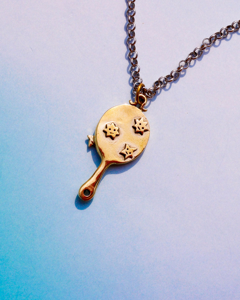 Gold necklace with a pendant shaped like a tiny hand mirror with stars motifs