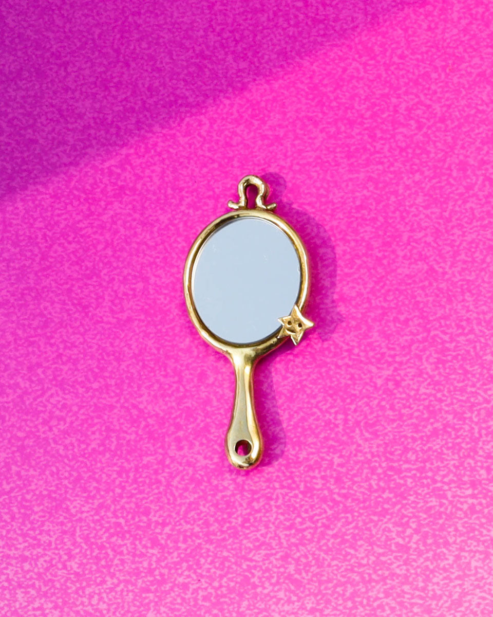 Gold-handled mirror charm on a pink background, handamde miniature tiny hand mirror in brass