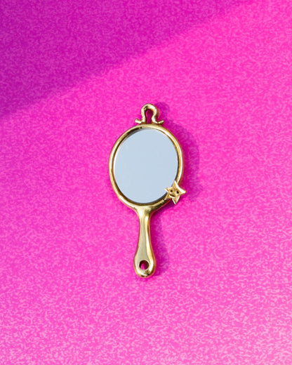 Gold-handled mirror charm on a pink background, handamde miniature tiny hand mirror in brass