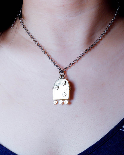 necklace with an arched-shaped mirror with stars design pendant on a person's neck