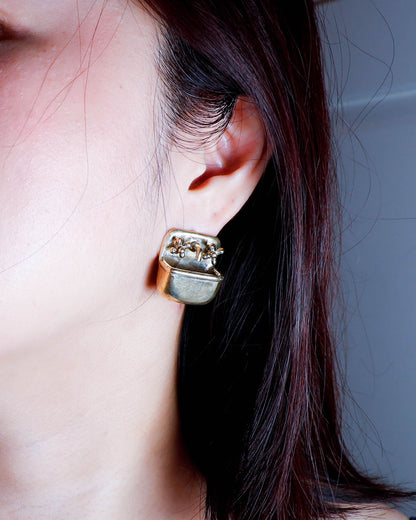 a person wearing a Miniature tiny sink earring in solid brass with sterling silver post, featuring movable faucet knobs and a detailed cast design inspired by a household bathroom sink