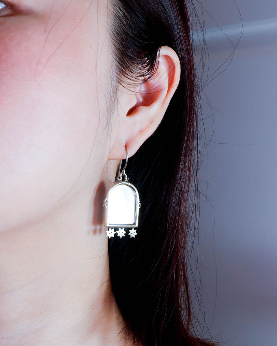 Earring of an arched-shaped mirror with stars design, wore on a person's ear