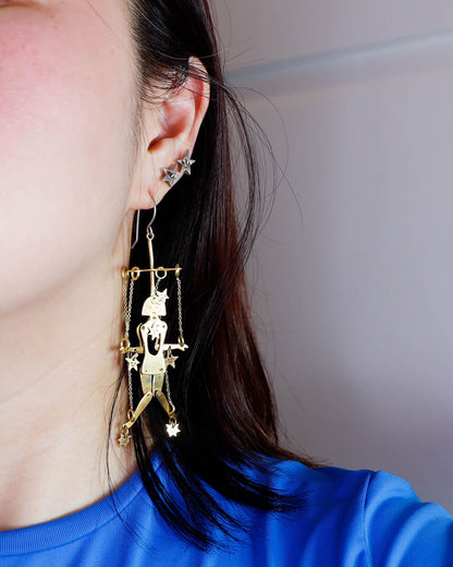Close-up of mini brass articulated puppet earring with stars, handmade kinetic jewelry