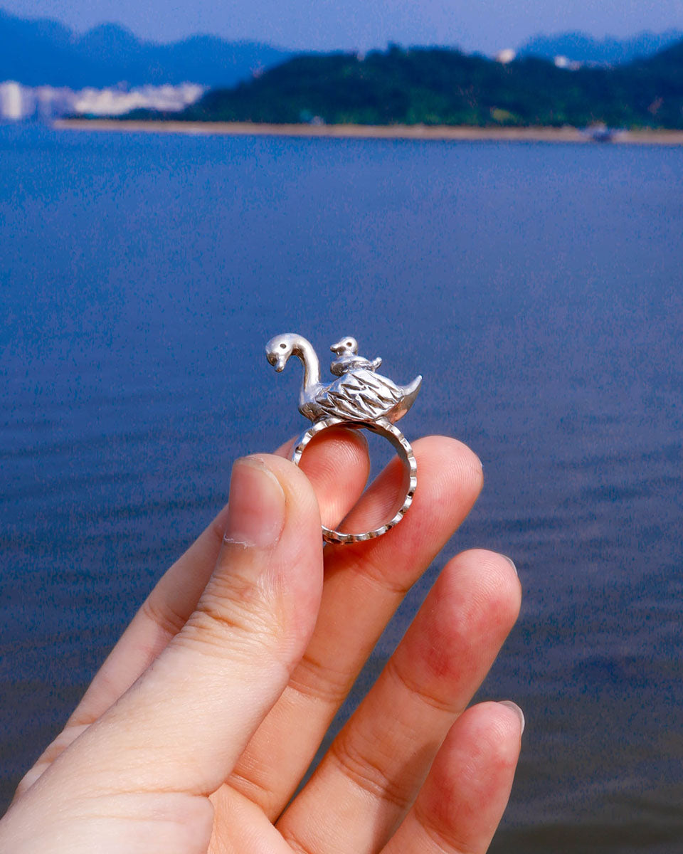 Handmade swan ring in sterling silver photographed beside water
