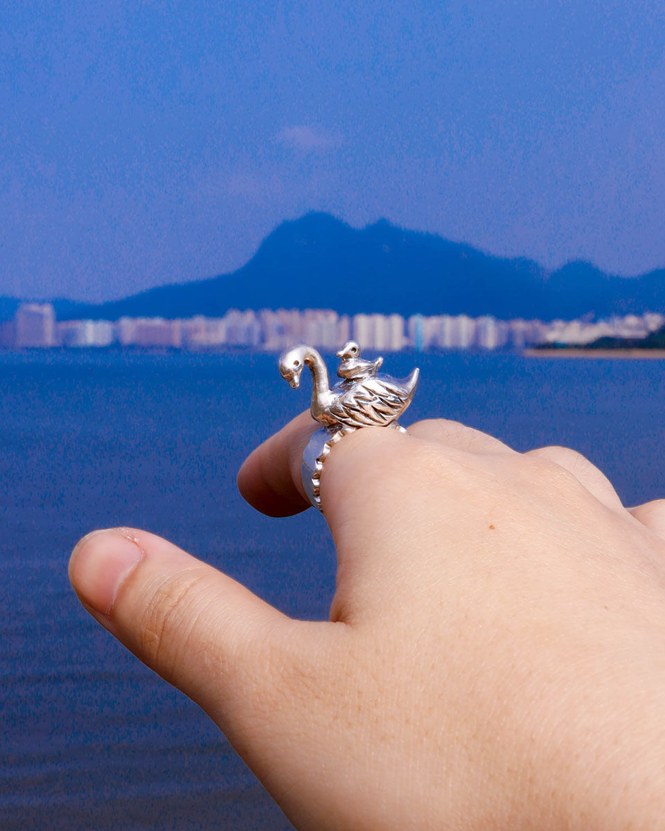 Hand wearing sterling silver swan and cygnet ring inspired by a moonlit lake